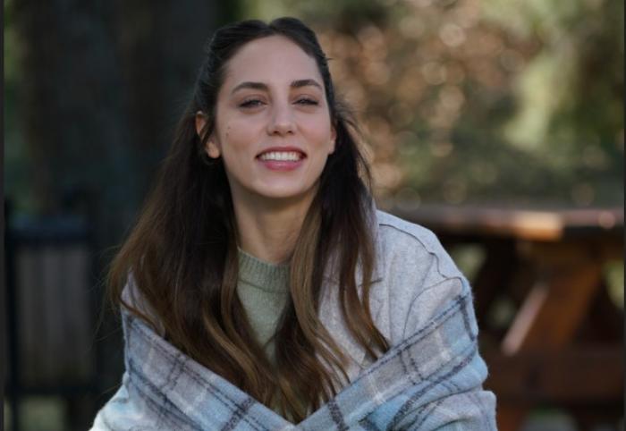 Öykü Karayel poartă părul lung, desprins și zâmbește