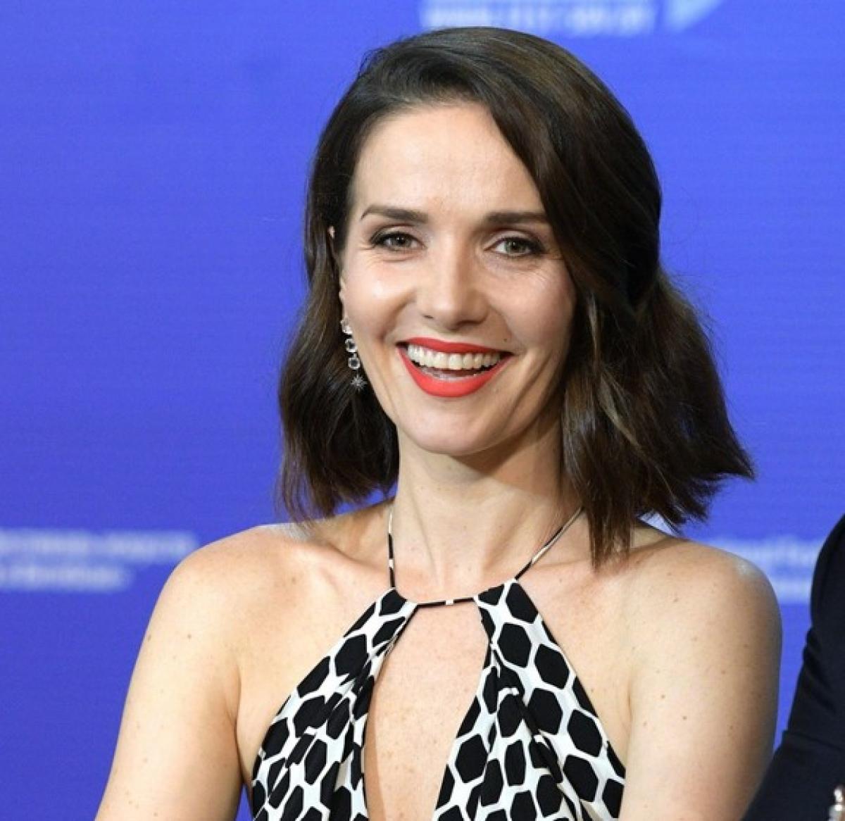 Natalia Oreiro poartă o rochie fără mâneci, părul scurt și zâmbește