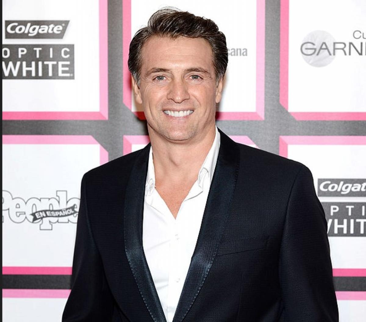 Juan Soler poartă o cămașă albă și un sacou negru și zâmbește