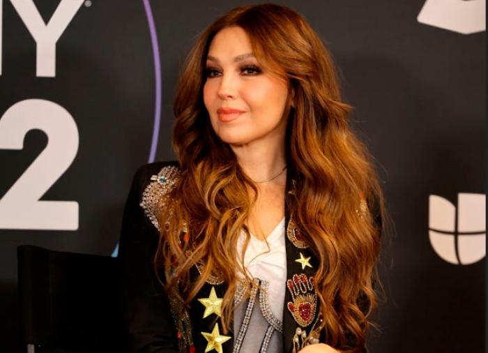 Thalia poartă o bluză albă și un sacou negru