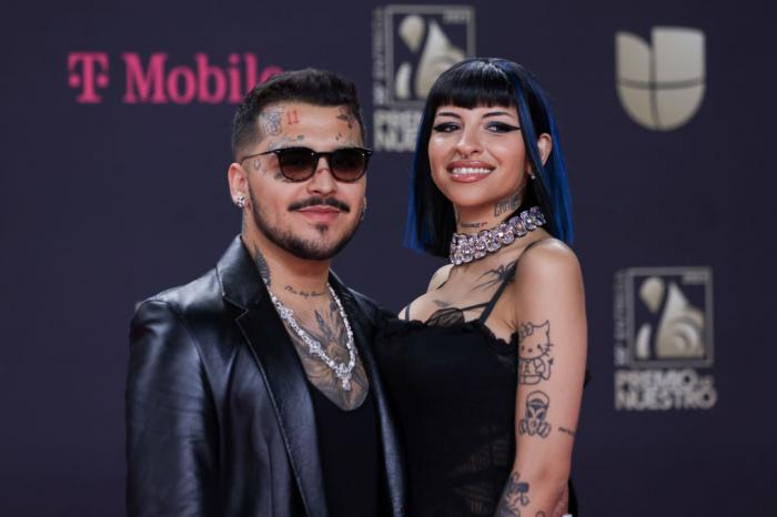 Christian Nodal poartă un tricou negru, ochelari de soare și stă lângă Julieta Emilia Cazzuchelli