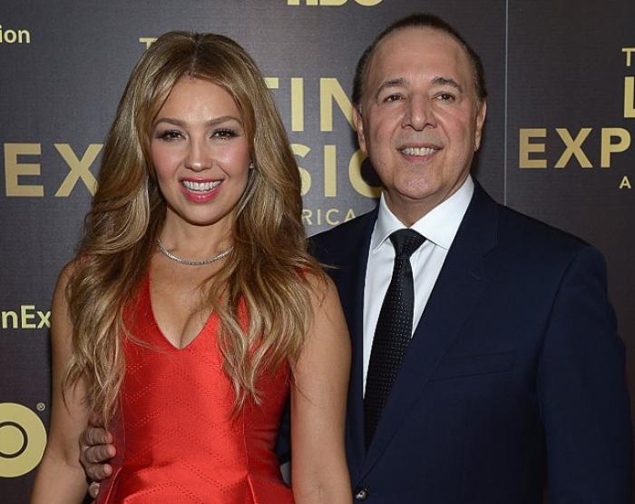 Thalia poartă o rochie roșie și stă lângă Tommy Mottola