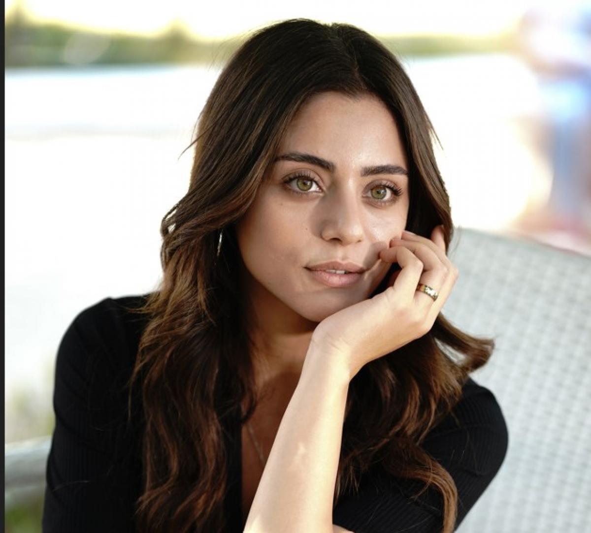 Sıla Türkoğlu poartă o rochie neagră și își ține mâna în dreptul obrazului