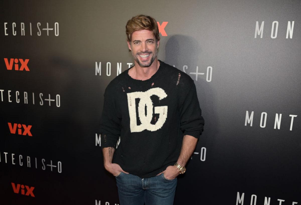 William Levy poartă o bluză neagră cu mâneci lungi și blugi și își ține mâinile în buzunare