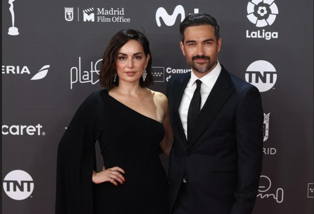 Alfonso Herrera poartă un costum negru și stă lângă Ana de la Reguera care poartă o rochie neagră cu un umăr gol