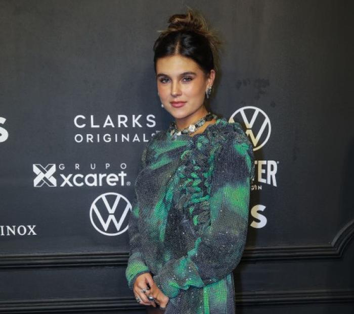 Romina Poza poartă o rochie verde și își ține mâinile împreunate în față