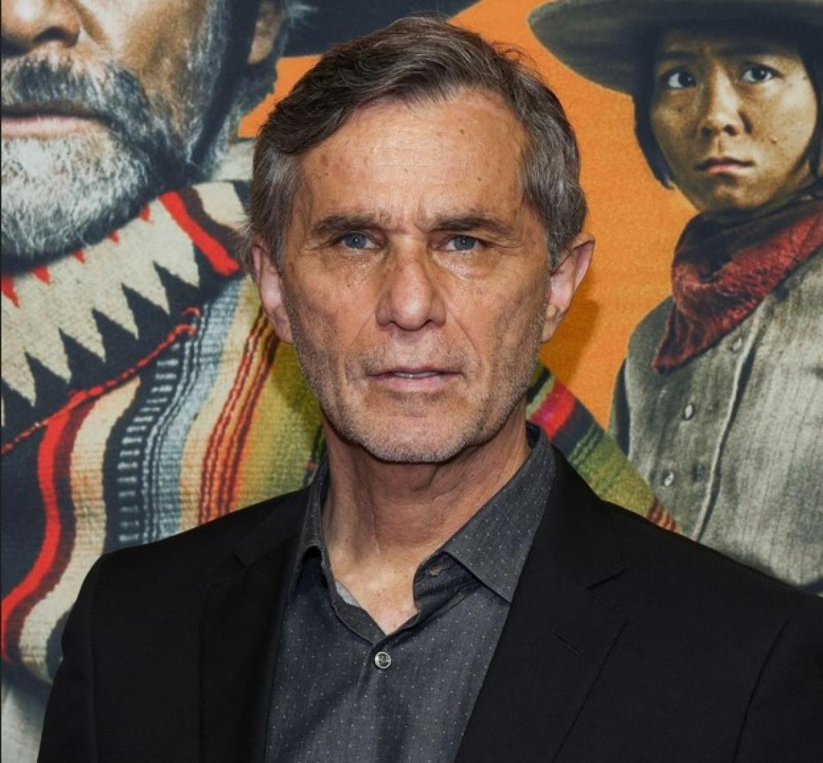 Humberto Zurita poartă o cămașă închisă la culoare și un palton negru