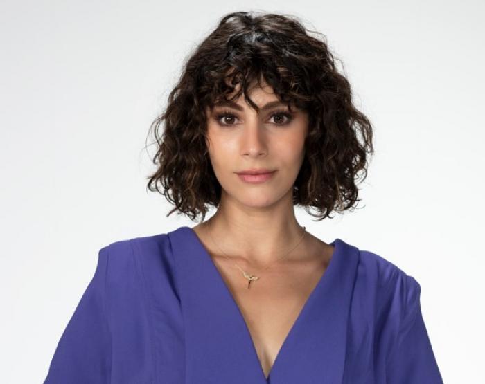 Tuğçe Açıkgöz poartă o bluză albastră cu mâneci lungi