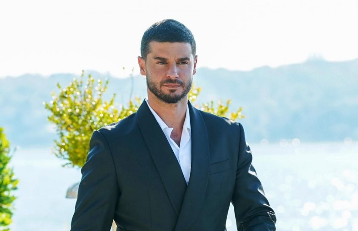 Berk Oktay poartă un costum închis la culoare