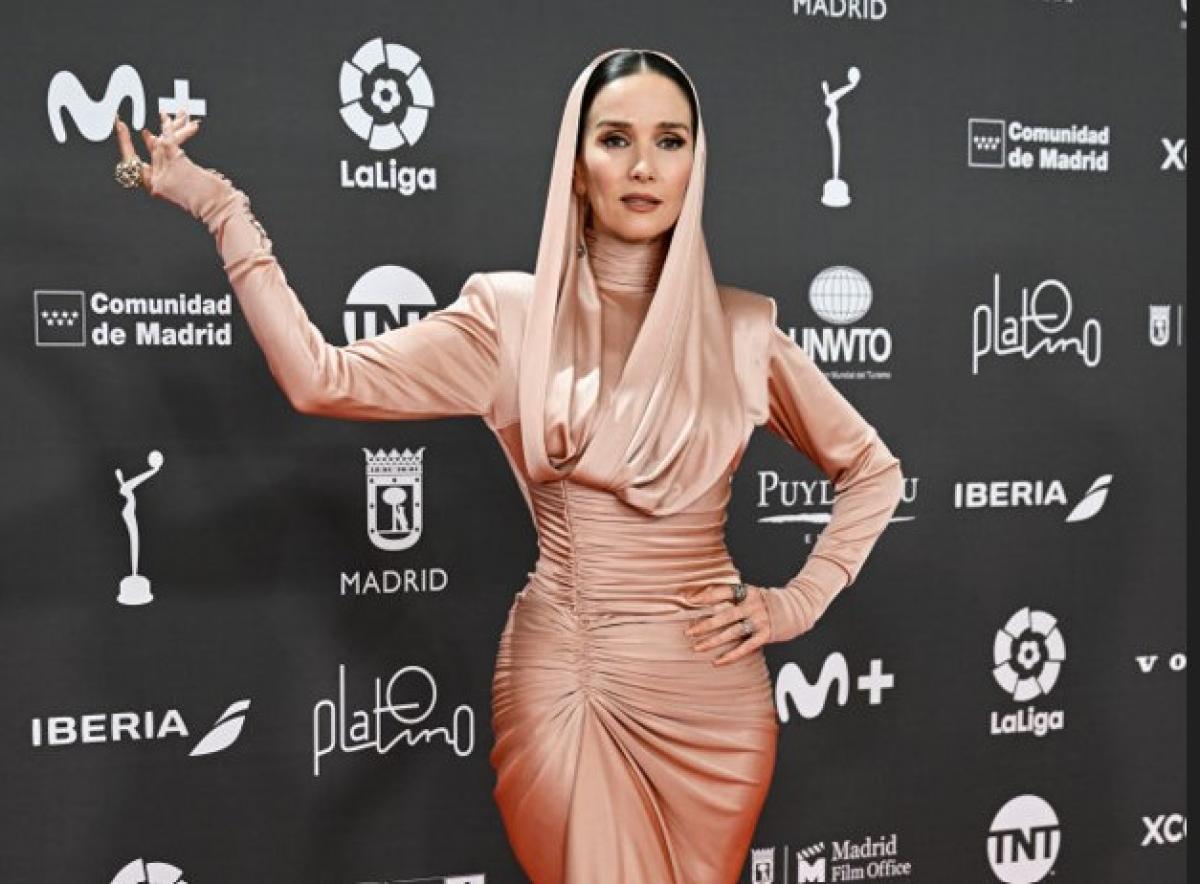 Natalia Oreiro poartă o rochie mulată și ține mâna dreaptă ridicată