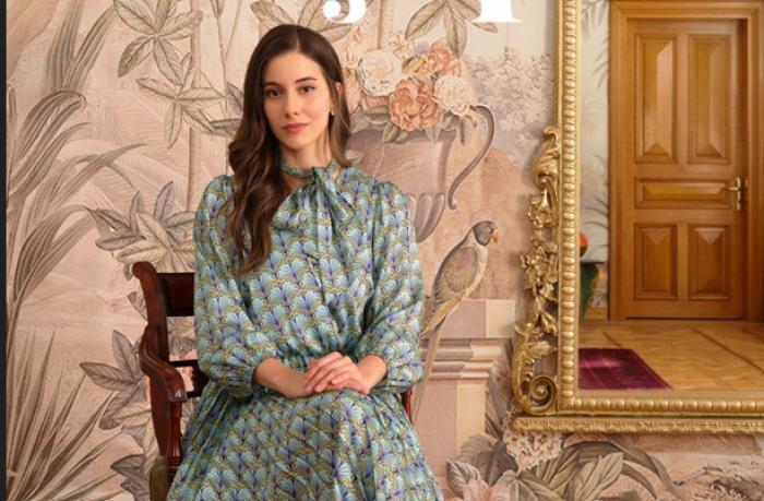 Beril Pozam poartă o rochie lungă și stă pe scaun