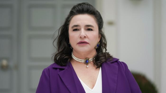 Esra Dermancıoğlu poartă o bluză albă și una mov și are părul desprins