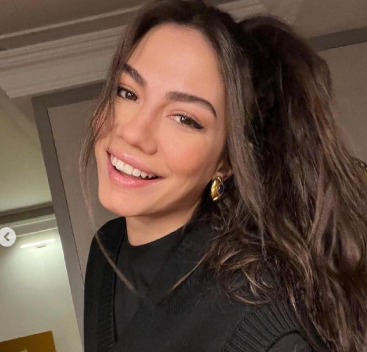 Demet Özdemir poartă părul lung, desprins și zâmbește