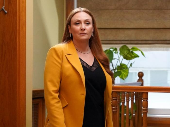 Gülçin Santırcıoğlu poartă un sacou portocaliu și o bluză neagră