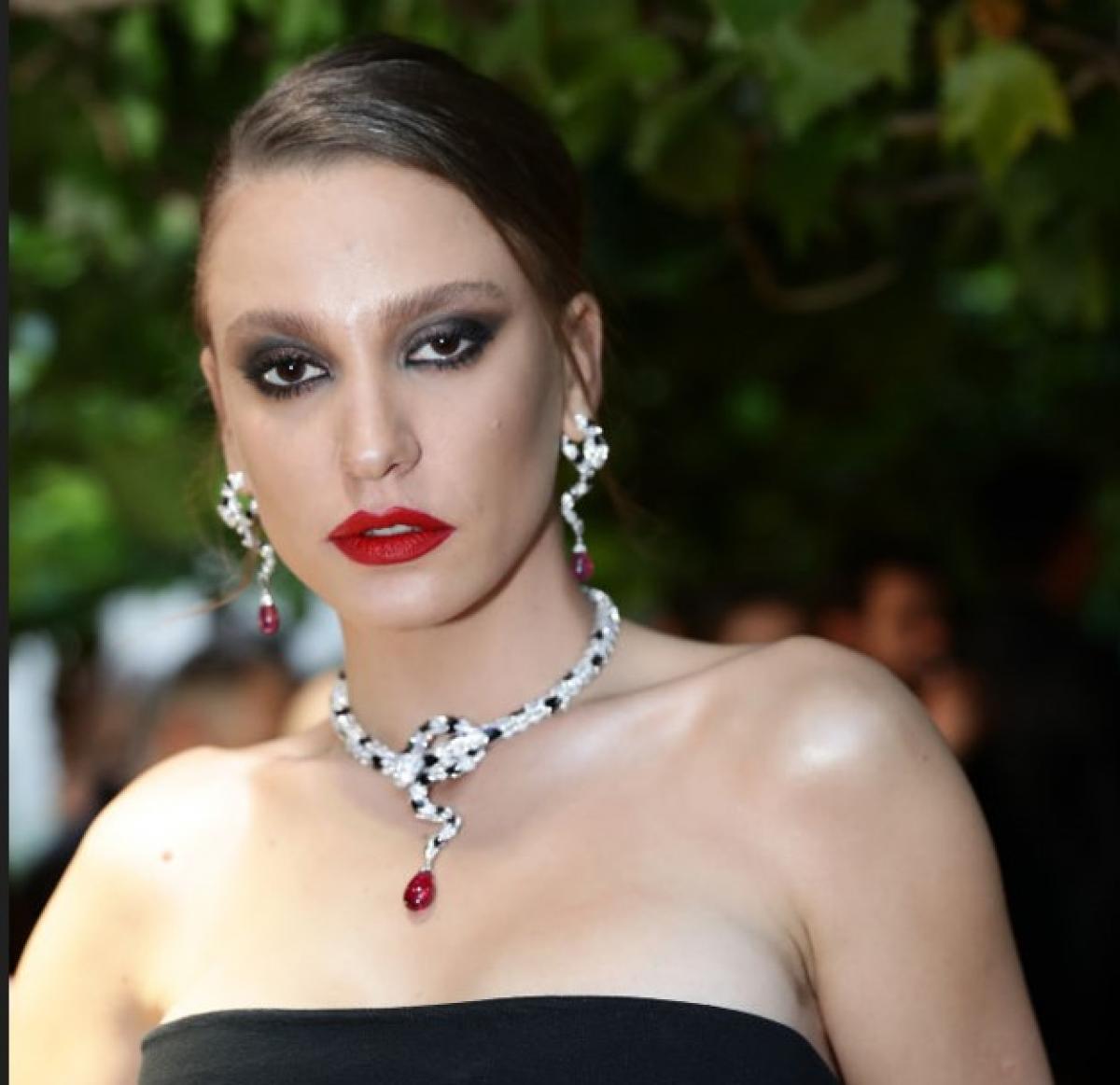 Serenay Sarıkaya poartă o rochie neagră fără mâneci, ruj roșu și părul prins