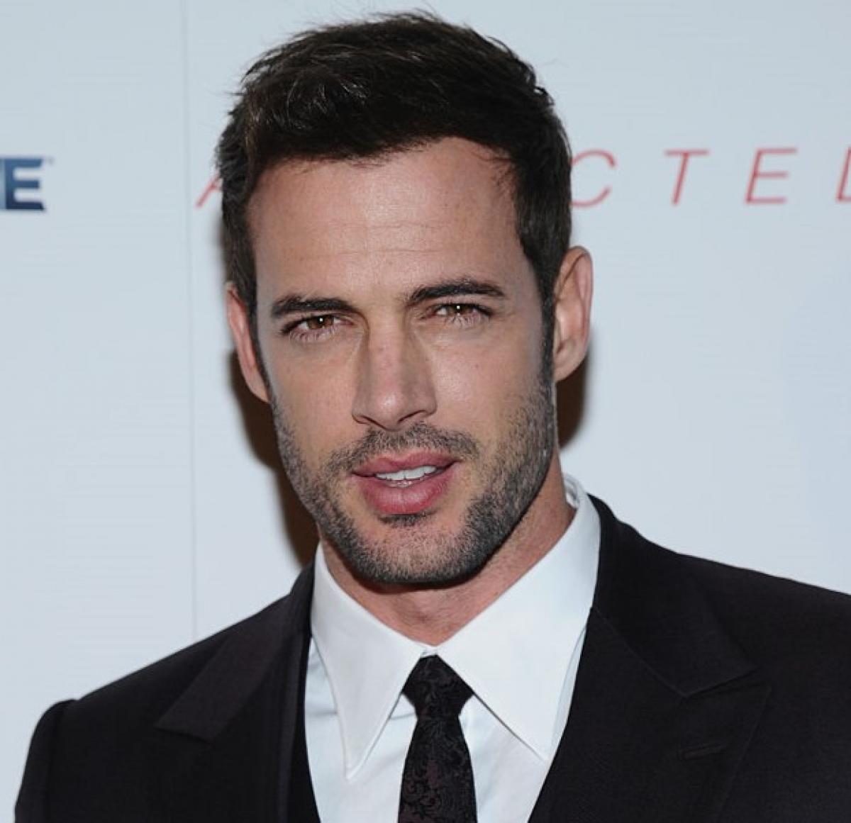 William Levy poartă un costum negru, cămașă albă și cravată neagră