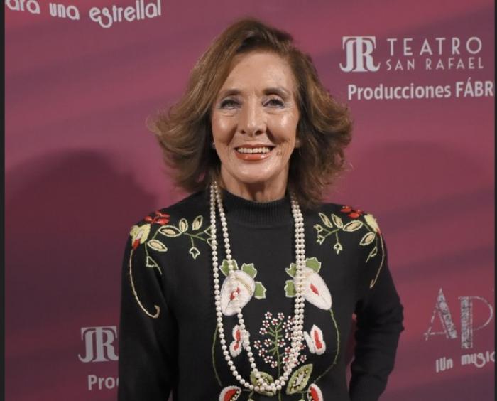 Lorena Velázquez poartă o rochie neagră cu mâneci lungi și zâmbește