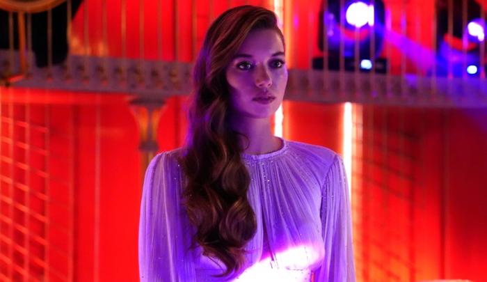 Afra Saraçoğlu poartă o rochie albă cu mâneci lungi și are părul desprins