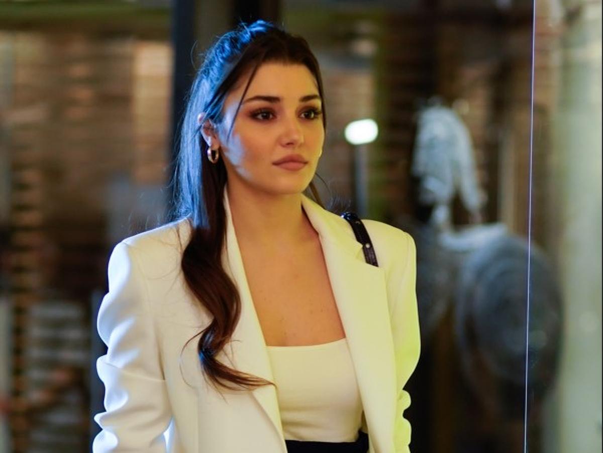 Hande Erçel poartă o bluză albă și un sacou alb cu mâneci lungi