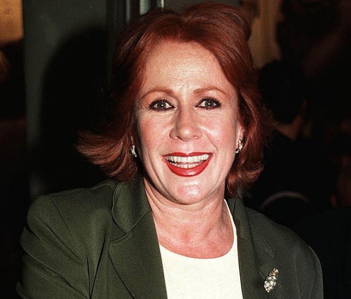 Laura Zapata poartă o bluză albă și un sacou verde închis și zâmbește