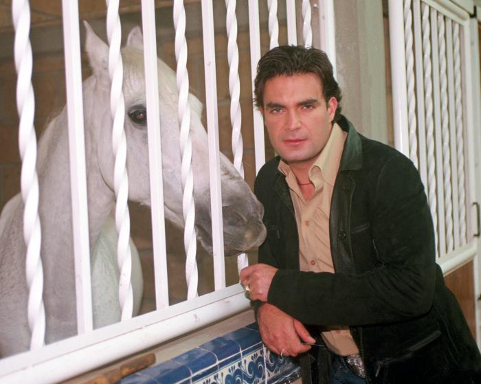 Mauricio Islas poartă o geacă neagră și stă aproape de un cal