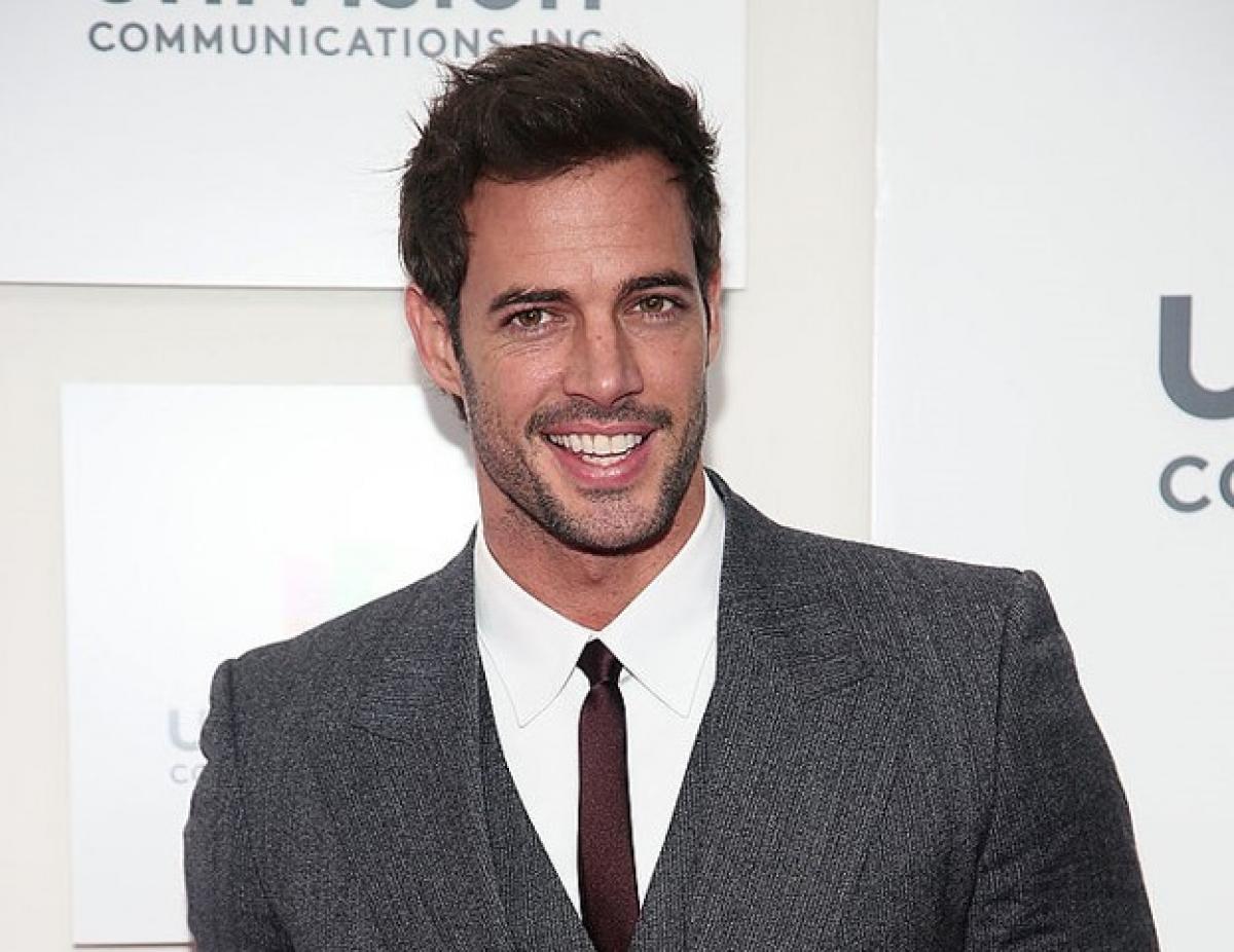 William Levy poartă o cămașă albă, o cravată subțire și un costum gri