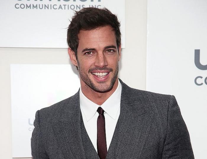 William Levy poartă o cămașă albă, o cravată subțire și un costum gri