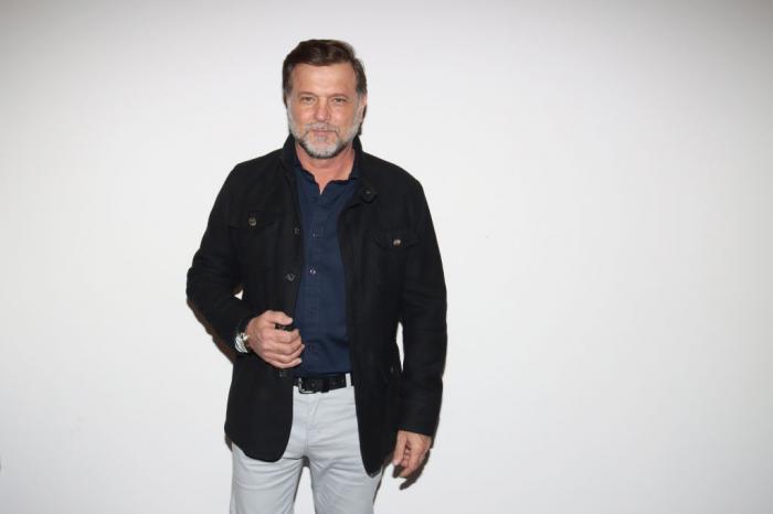 René Strickler poartă pantaloni deschiși la culoare, o geacă neagră