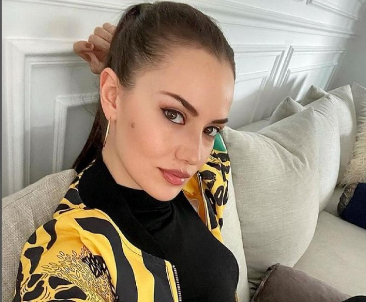 Fahriye Evcen poartă o bluză neagră și o jachetă colorată, are părul prins într-o coadă de cal