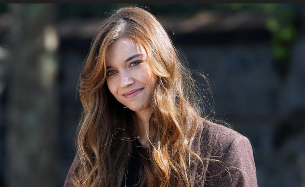 Afra Saraçoğlu poartă părul lung, desprins și zâmbește