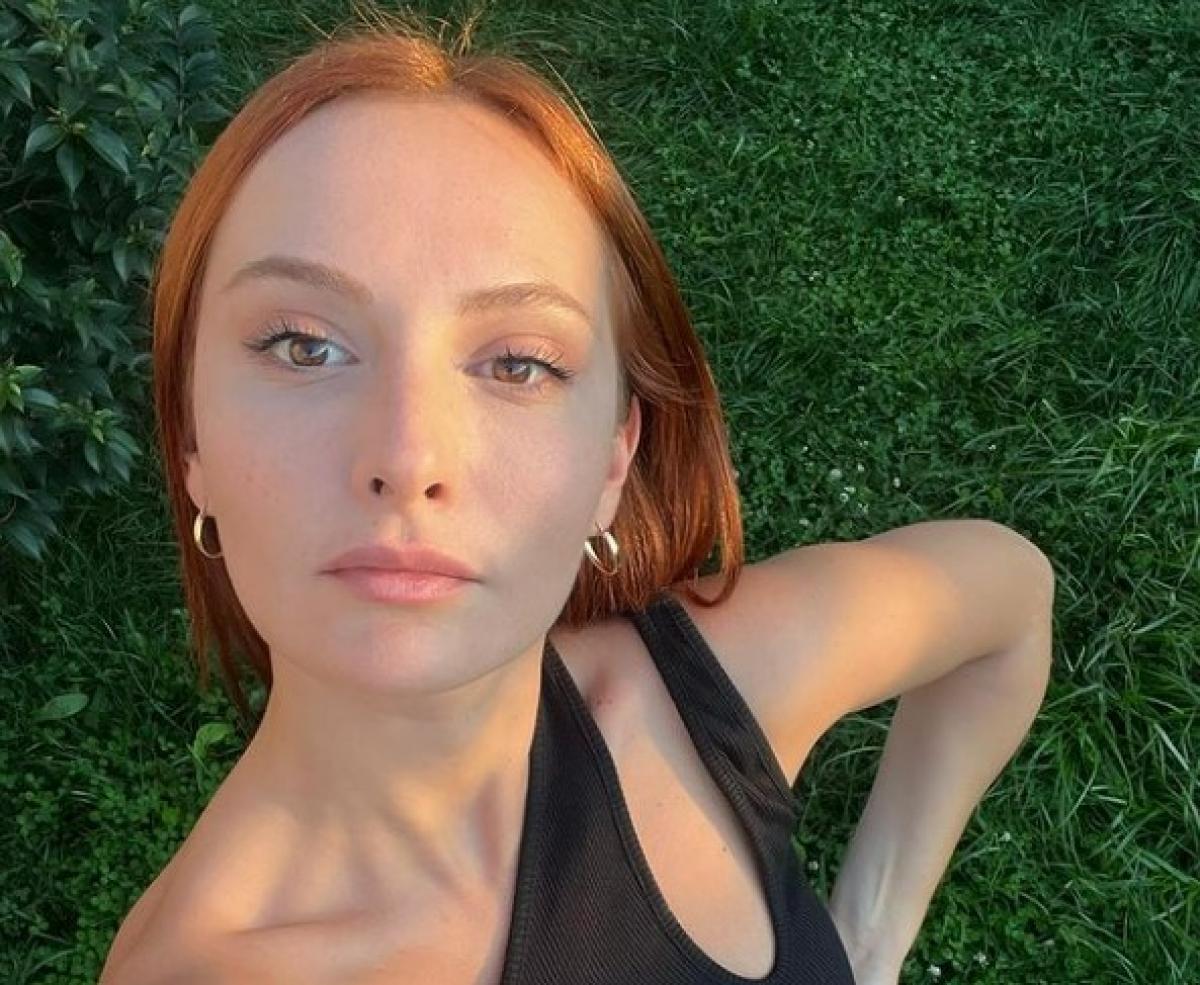 Başak Gümülcinelioğlu poartă o rochie neagră fără mâneci și are părul roșcat