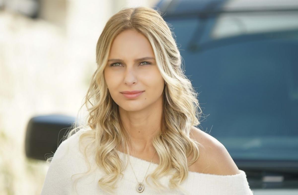 Jessica May poartă un pulover alb cu mâneci lungi