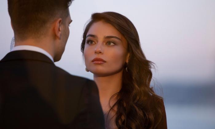 Ayça Ayşin Turan poartă o rochie neagră cu mâneci lungi și are părul desprins