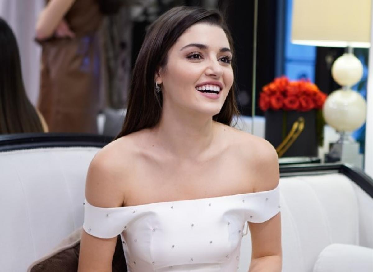 Hande Erçel poartă o rochie albă și zâmbește