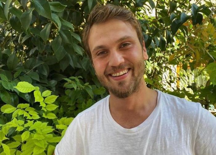 Aras Bulut İynemli poartă un tricou alb și zâmbește