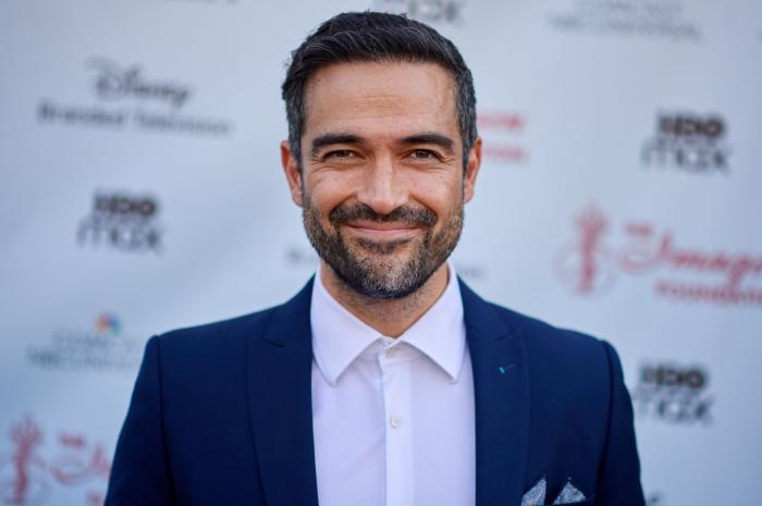 Alfonso Herrera poartă o cămașă albă și un sacou închis la culoare