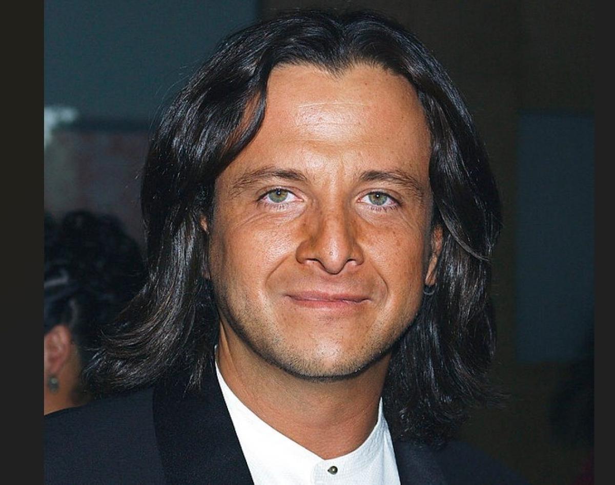 Eduardo Palomo poartă o cămașă albă și un sacou negru