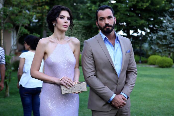 Serdar Özer poart un costum gri și cămașă deschisă la culoare