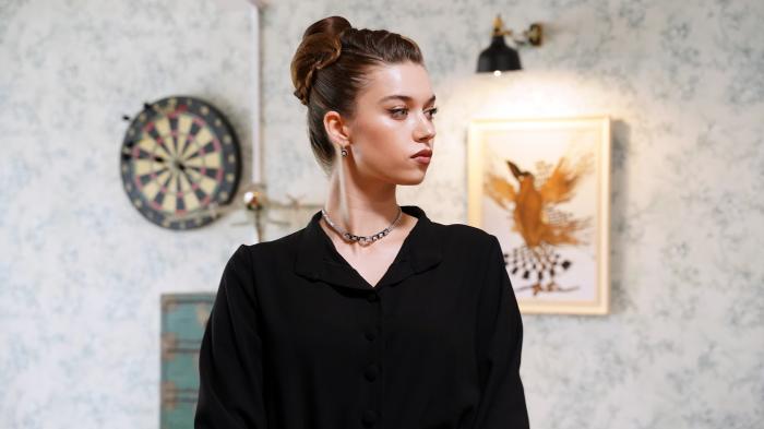 Afra Saraçoğlu poartă o rochie neagră și părul prins în coc