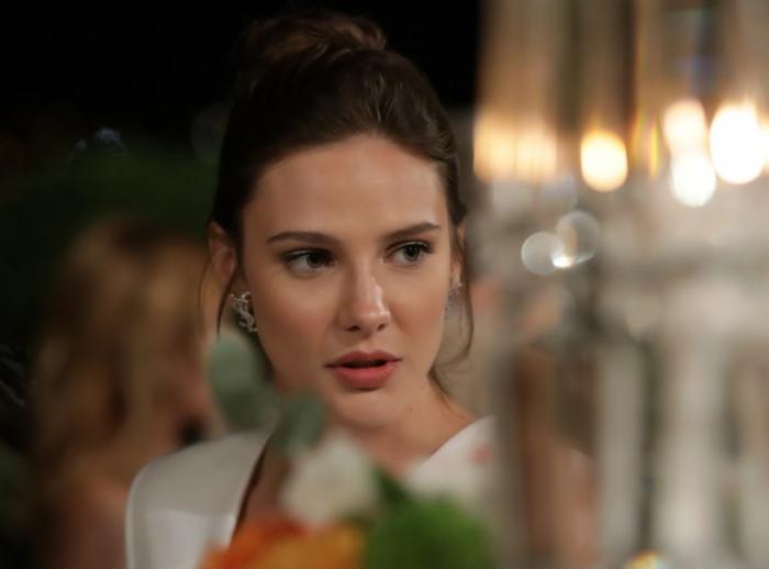 Alina Boz poartă un costum alb și are părul prins