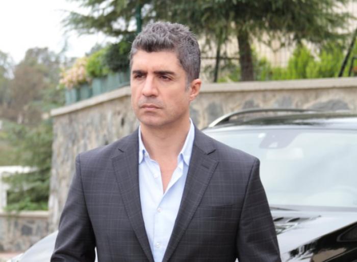 Özcan Deniz poartă costum și cămașă