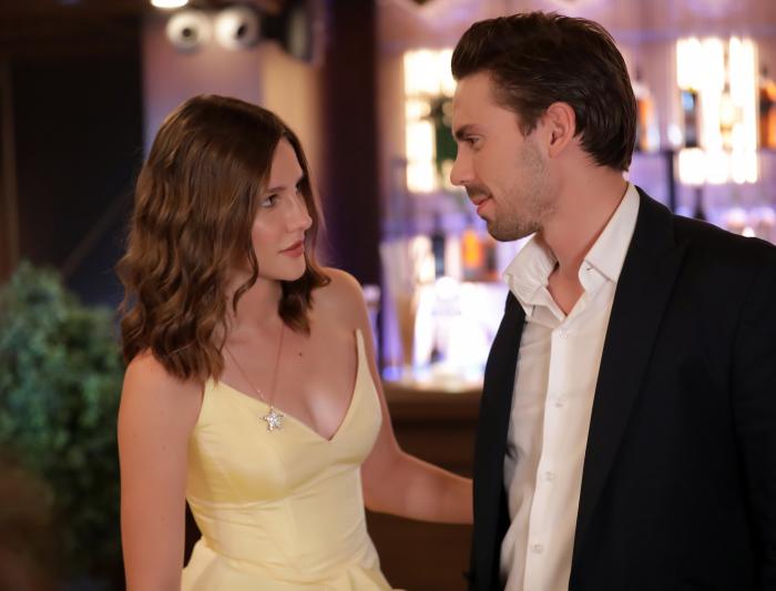 Actrița poartă o rochie galbenă și actorul un sacou negru și o cămașă albă