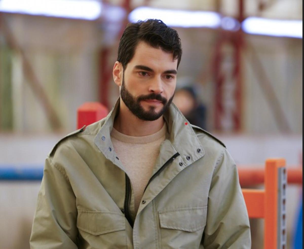 Akın Akınözü poartă o geacă de culoare grij deschis