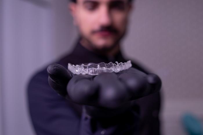 o mână întinsă cu un aparat dentar