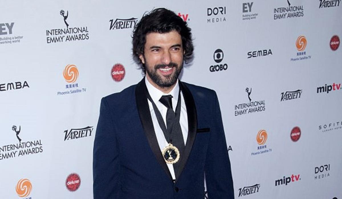 Engin Akyürek poartă o cămașă albă și un sacou închis la culoare