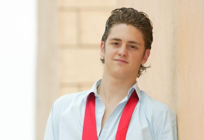 Christopher Uckermann poartă o cămașă albastră și o cravată roșie