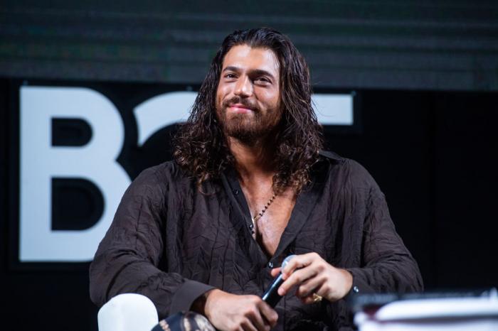 Can Yaman poartă o cămașă neagră și părul desprins