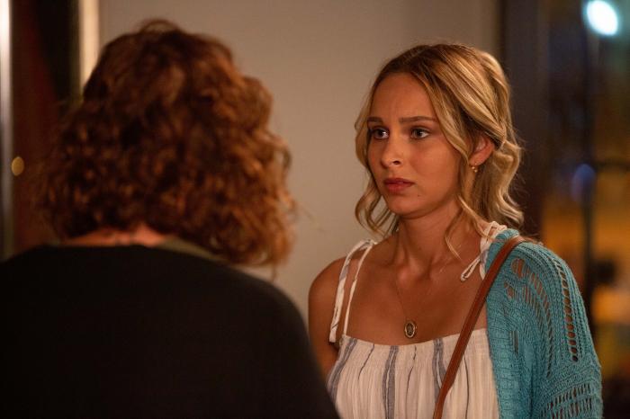 jessica May poartă o bluză albă și un pulover albastru