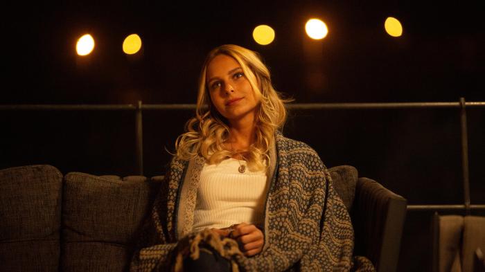 Jessica May poartă un tricou alb și un pulover