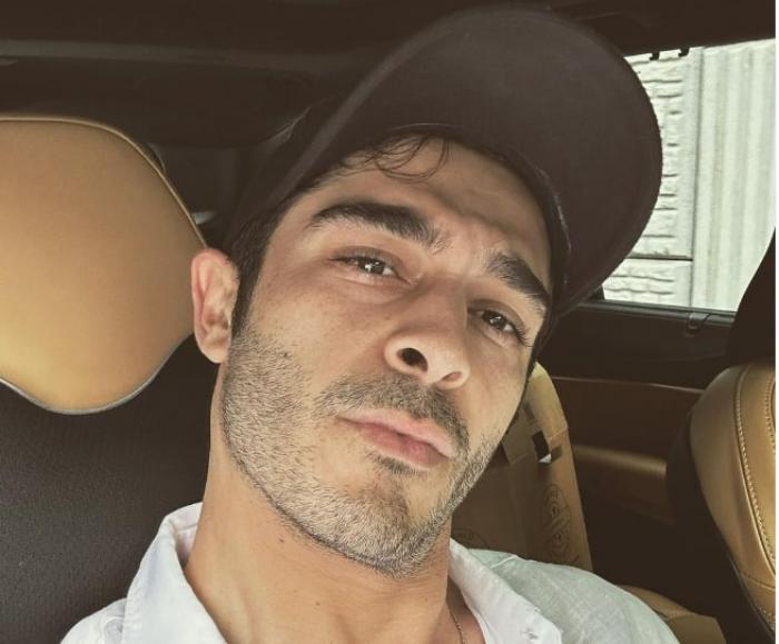 actor poartă șapcă și cămașă albă